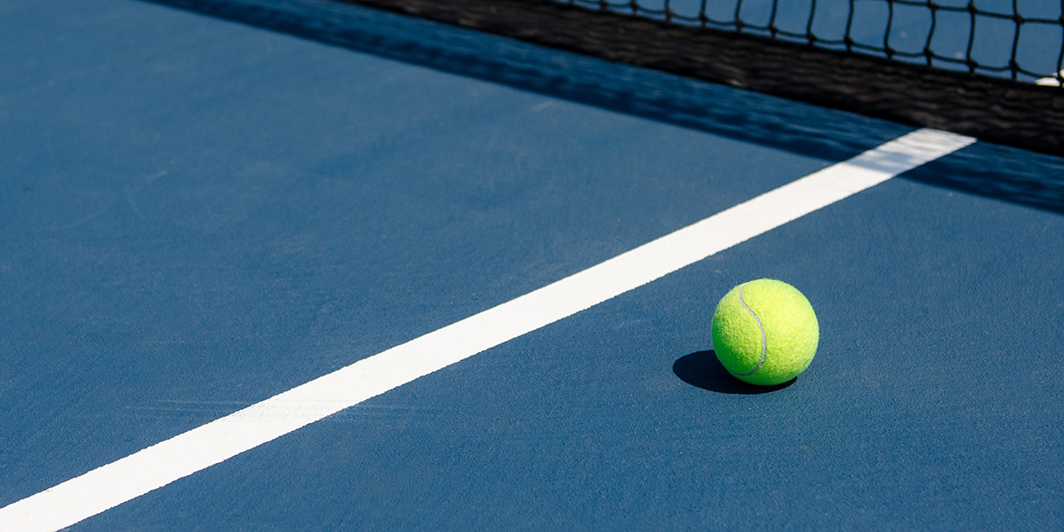Yellow tennis ball on a blue tennis court