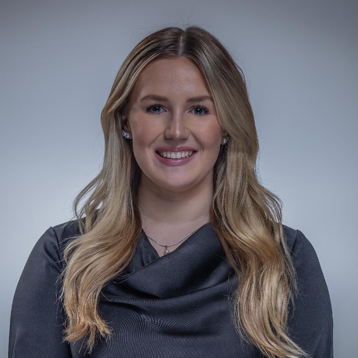 Kaylee Dean smiles for a photo against a gray background.