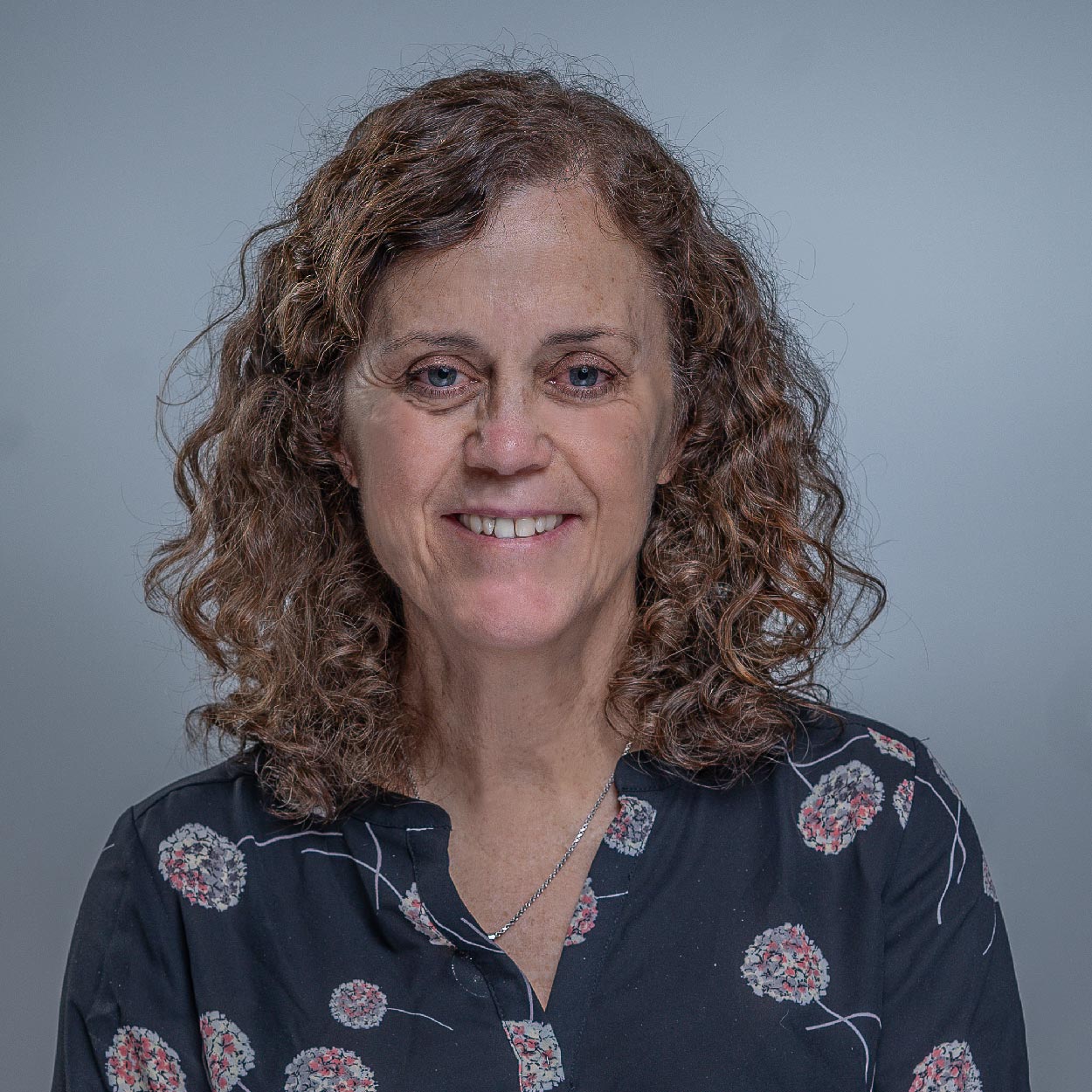 Patricia Bramlet smiles for a photo against a gray background.