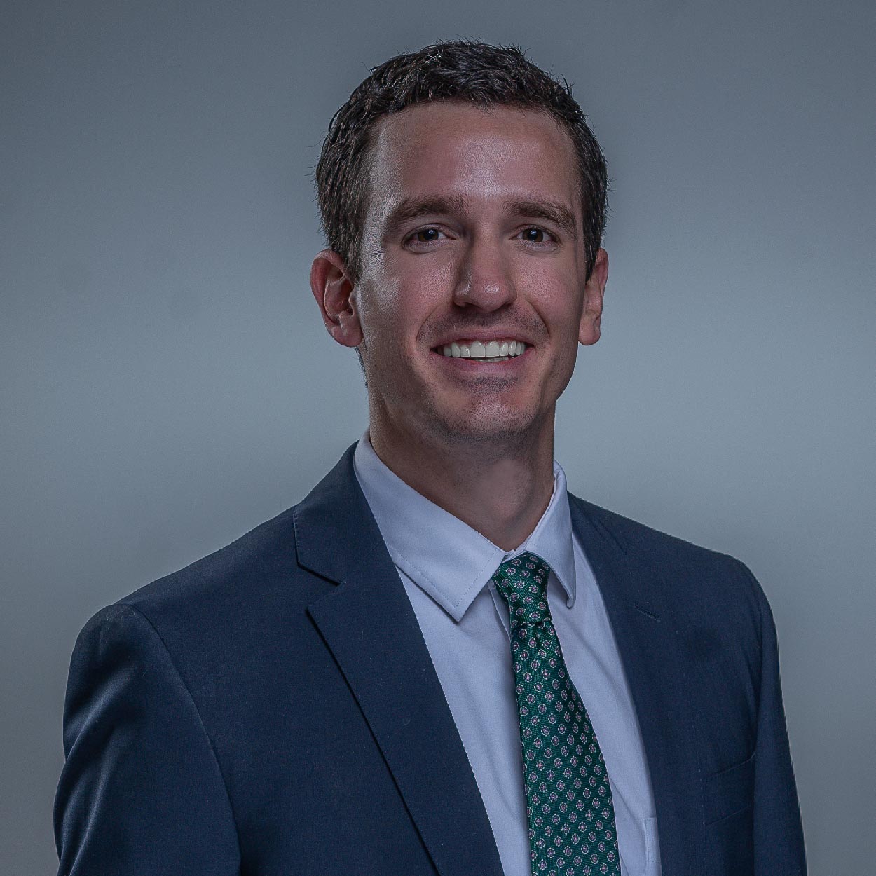 Sam Gentry smiles for a photo against a gray background.